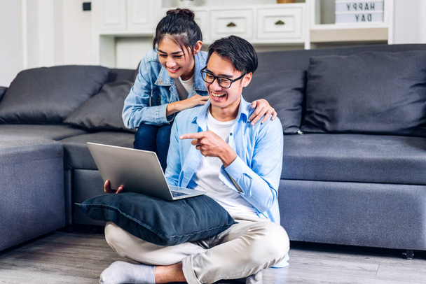 Young asian couple relaxing using laptop computer work and video conference meeting online chat.Creative business couple planning strategy analysis and brainstorm at home - 写真・画像