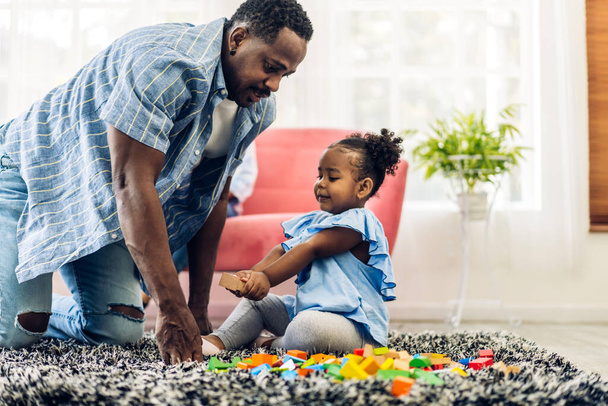 Портрет счастливой любви чернокожего семейства африканский отец с маленькой девочкой улыбается деятельности учиться и навыки мозговой тренировки играть с игрушечной сборки деревянных блоков настольная учебная игра дома. - Фото, изображение