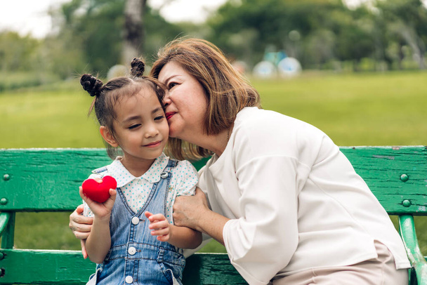 Retrato de amor feliz abuela asiática y pequeña chica linda asiática disfrutar de relajarse en el parque de verano.Chica joven con su abuelo sonriendo juntos. - Foto, Imagen