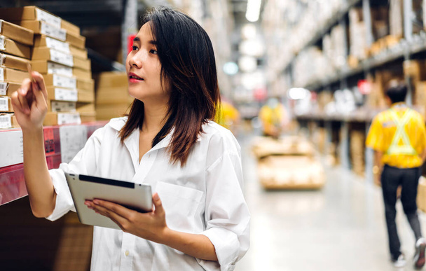 Portrait asian engineer woman shipping order detail on tablet check goods and supplies on shelves with goods background inventory in factory warehouse.logistic industry and business export - Photo, Image