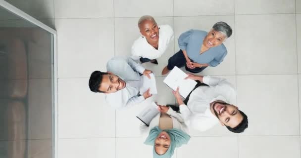 Collaboration, overhead and huddle with a business team laughing while working together in an office. Face, teamwork and documents with a man and woman employee group standing in a circle from above. - Footage, Video