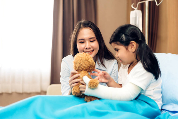 Ασιατική χαμογελαστή γυναίκα γιατρός υπηρεσία βοηθήσει στην υποστήριξη συζητώντας και συμβουλεύοντας μιλήσει σε μικρό κορίτσι ασθενή δώσει αρκουδάκι και ελέγξτε τις πληροφορίες στο νοσοκομείο - Φωτογραφία, εικόνα
