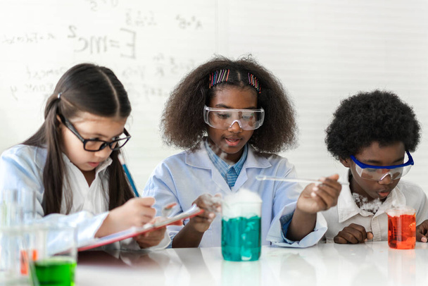 Eine Gruppe Jugendlicher lernt mit dem Lehrer Naturwissenschaften und studiert ein chemisch-naturwissenschaftliches Experiment und hält das Reagenzglas in der Hand im Experimentallabor auf dem Tisch in der Schul.Bildung - Foto, Bild