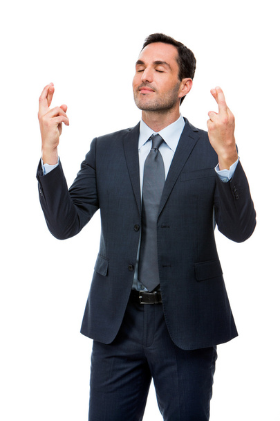 Half length portrait of a businessman with eyes closed and fingers crossed - Photo, Image