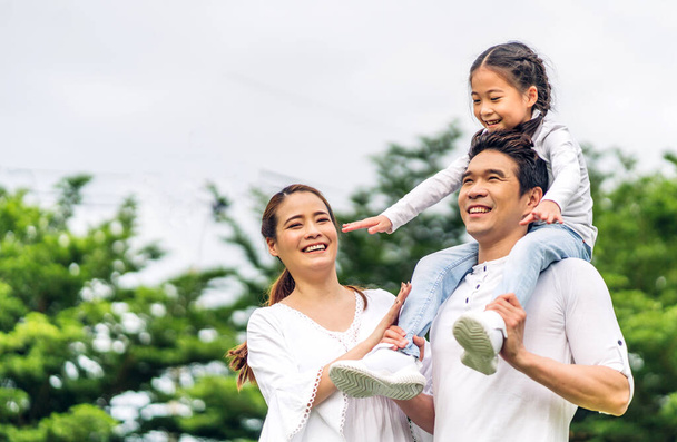 Portrait of enjoy happy love asian family father and mother holding hug cute little asian girl child smiling play and having fun moments good time in summer park at home - Foto, immagini