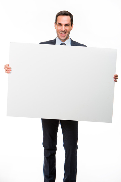 Full length portrait of a smiling businessman holding a white placard - Fotoğraf, Görsel