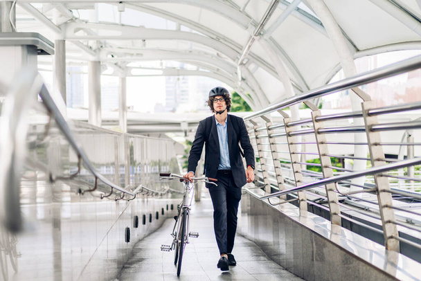 Portrait of hipster handsome businessman in suit with backpack walk and hold riding bicycle on the street city way go to work.business travel transport bike concept - Fotó, kép