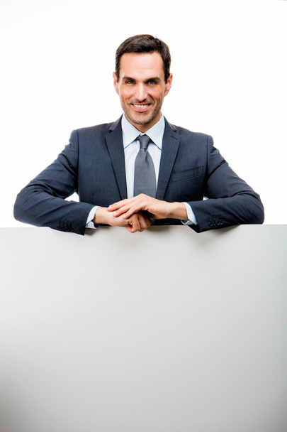 Половина портрета улыбающегося бизнесмена, опирающегося на белый плакат
 - Фото, изображение