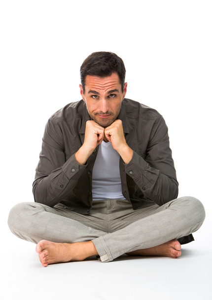 Thoughtful man sitted on the floor, looking at camera, with the hands under his chin - Foto, imagen