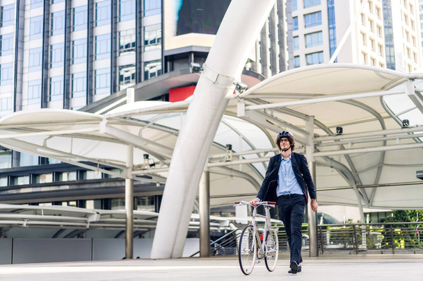 Portrait of hipster handsome businessman in suit with backpack walk and hold riding bicycle on the street city way go to work.business travel transport bike concept - Fotoğraf, Görsel