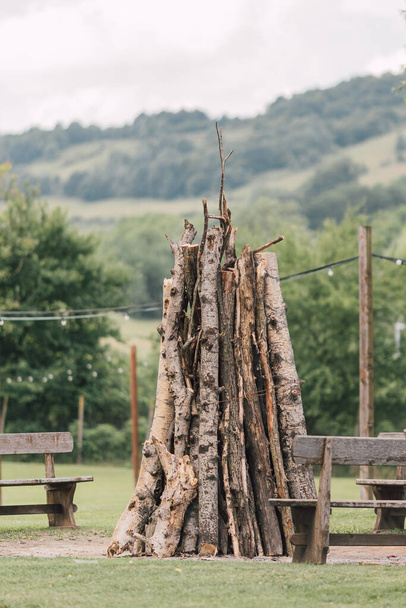 Pile of logs for a campfire in natural park. Stack of firewood standing in countryside for a outdoor group activity. Outdoors lifestyle.   - 写真・画像