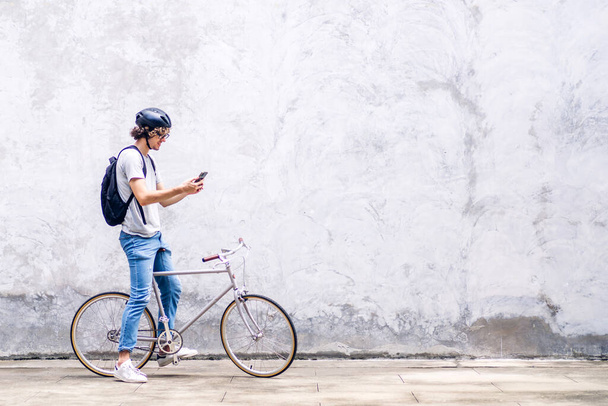 Ritratto di un affascinante uomo d'affari casual hipster con zaino che guarda sullo smartphone mentre si spostano in bicicletta sulla strada per andare al lavoro.Concetto di bici da viaggio per affari - Foto, immagini
