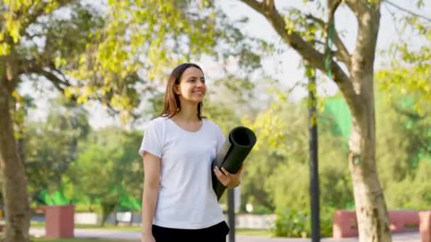Indian woman walking with Yoga mat in a park in morning time - Materiał filmowy, wideo