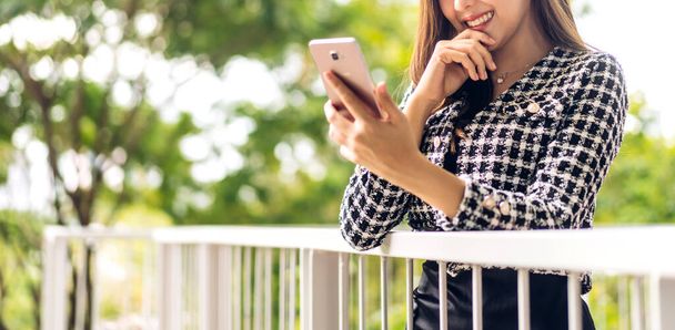 Gülümseyen mutlu Asyalı kadın portresi dijital akıllı telefon kullanarak rahatlıyor. Ekran daktilo mesajlarına bakan ve oyun oynayan Asyalı genç kız veya sosyal medya - Fotoğraf, Görsel