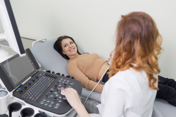 a female doctor performs ultrasound diagnostics of the intestine, abdominal cavity, right lobe, liver, bile ducts, gallbladder. Soft tissue examination using a portable sensor device with a convex probe. - Foto, Imagen