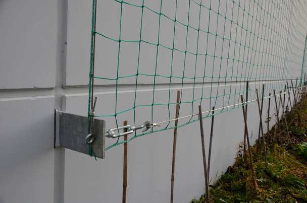 metal trellises made of interconnected stainless steel cables attached to the wall of house grow and wrap vine. column tunnel. detail of mesh clamps, grip, holder, twisted, creeper, fallen tree - Foto, Imagem