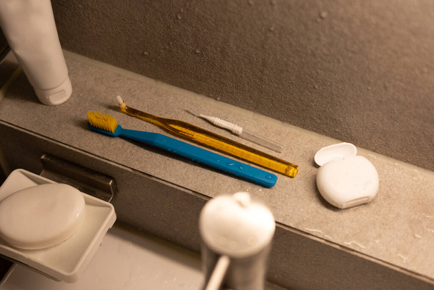 Различные зубные щетки с зубной нитью в ванной комнате - Фото, изображение