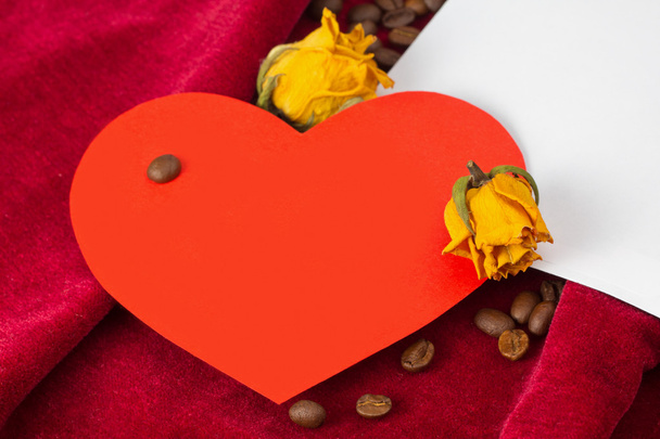 Czerwone serce leżące na kopercie z suszonych róż i kawa - Zdjęcie, obraz