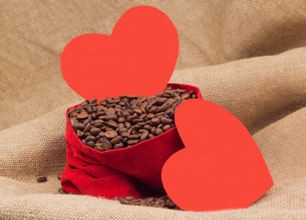 Dos corazones de papel rojo con granos de café en saco de terciopelo rojo
 - Foto, imagen