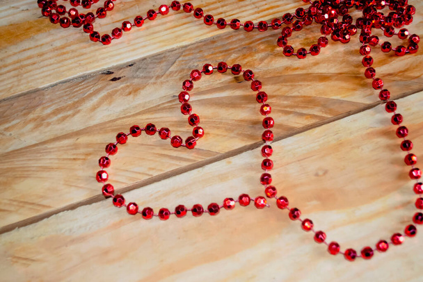 Серце вистелене червоними намистинами на дерев "яному столі. Серце вистелене намистинами на столі. День Святого Валентина - валентин на столі з власними руками.. - Фото, зображення