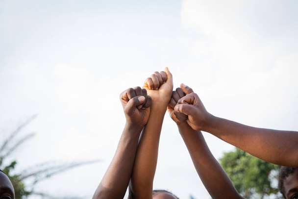 Four fists of African people united in sky, photo with copy space above - Zdjęcie, obraz