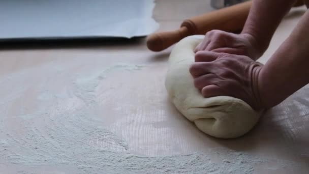adult woman kneading the dough in background rolling pin and baking sheet woman strongly hanging dough by hand homemade pastry pizza pies bread cottage in village family food food for poor - Video, Çekim