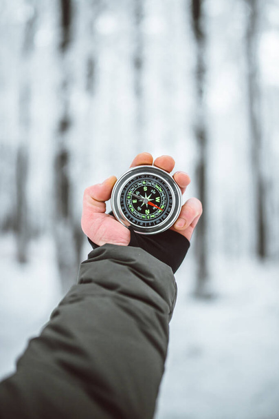 man holding compass in hand at winter time  - Φωτογραφία, εικόνα