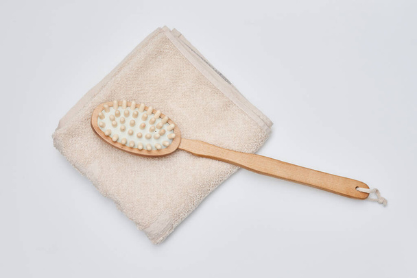 a wooden brush and towel on a white background with copy space in the bottom right hand is holding a toothbrush - Fotó, kép