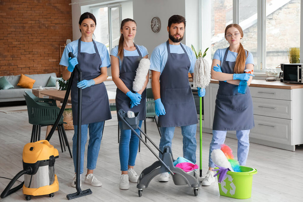 Young janitors with cleaning supplies in living room - Fotoğraf, Görsel