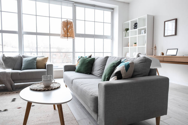 Interior of modern living room with grey sofas, window and shelving unit - Photo, image