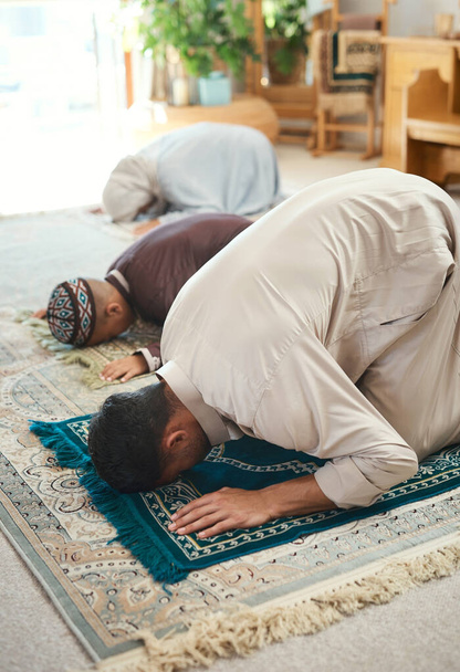 Prayer is as important as breathing. a young muslim couple and their son praying in the lounge at home - Foto, afbeelding