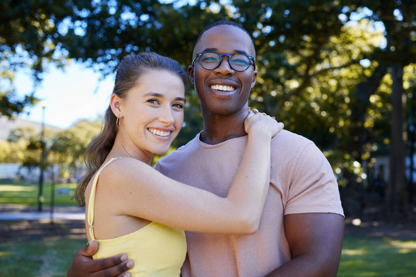 Interracial, portrait and couple hug, park or smile for relationship, romance or bonding. Love, black man or woman romantic in nature, loving or happiness with embrace, dating or quality time outdoor. - Foto, Imagem