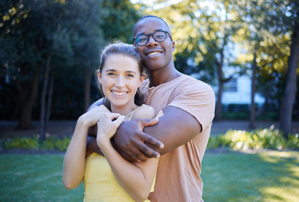 Couple in portrait, date in park with hug and outdoor in nature, love and commitment with interracial relationship. Trust, support and happy people, black man and woman smile on face with fresh air. - Foto, afbeelding