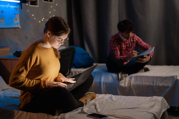 Students girl and guy studying in college dormitory at night. Student use laptop computer in dark domestic room. Copy space - Φωτογραφία, εικόνα