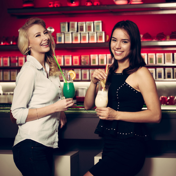 Two beautiful women drinking cocktail in a night club and having - Foto, immagini