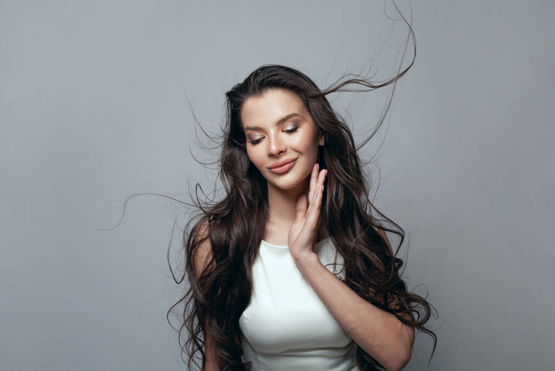 Beauty woman with healthy wavy hairdo on gray background - Foto, Imagen