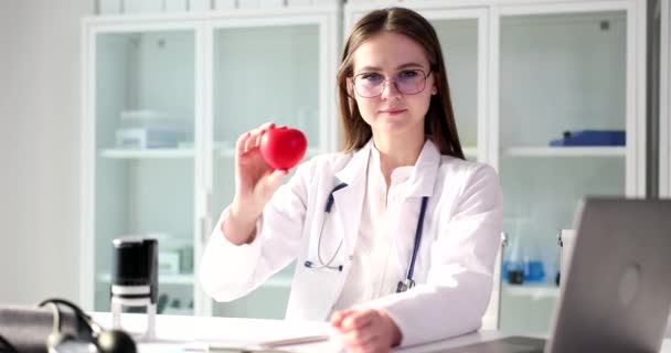 Woman doctor cardiologist holding red toy heart in hands. Internal organ transplantation and heart surgery - Felvétel, videó