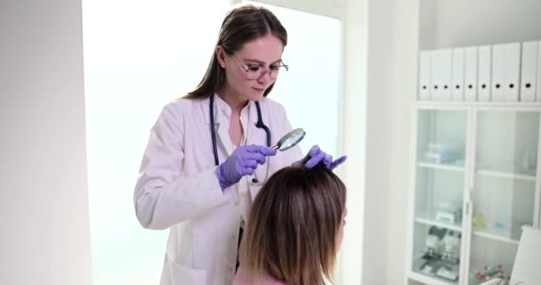 保護手袋の医者は虫眼鏡を通して患者の頭部の皮を検査する。脱毛のための栄養学者のアドバイス - 映像、動画