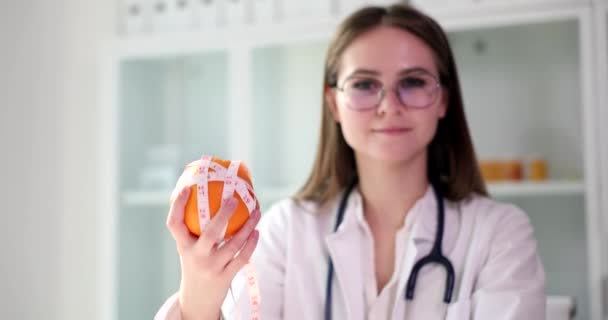Dietitian doctor holds orange fruit and centimeter. Diet healthy food and calories - Video