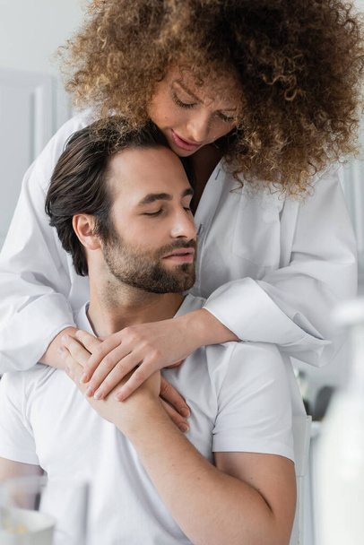 sensual young woman hugging bearded boyfriend in kitchen - Fotografie, Obrázek