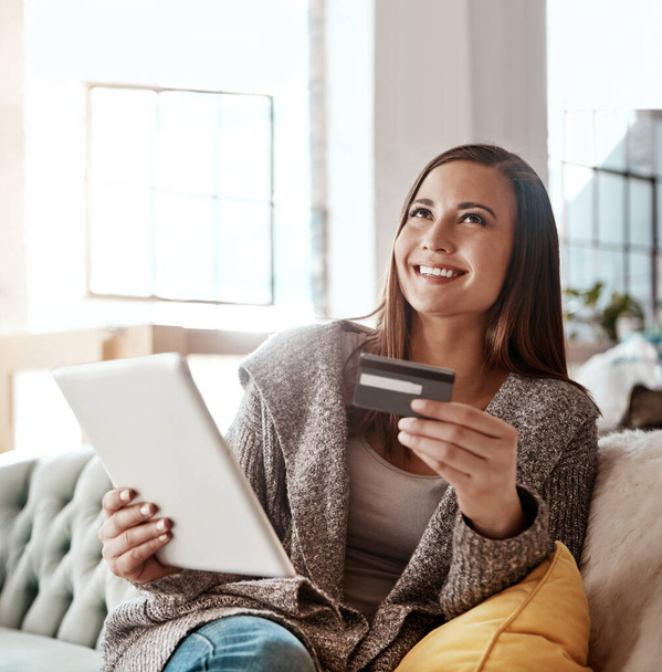 Thinking, credit card and online shopping on digital tablet by woman on sofa for payment or booking online. Idea, girl and online banking with debit card for credit score, purchase and online order. - Photo, Image