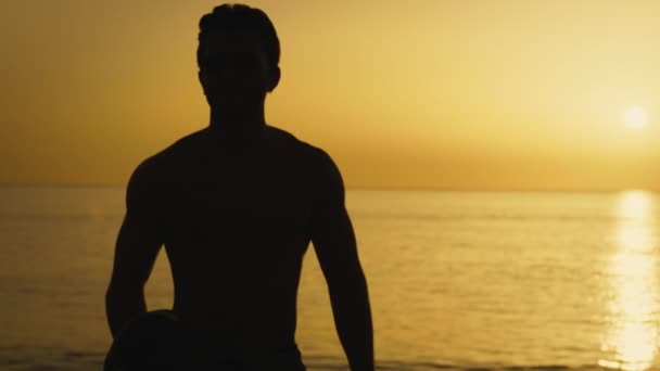 Silhouette of a man at sunset with American football ball. - Filmati, video