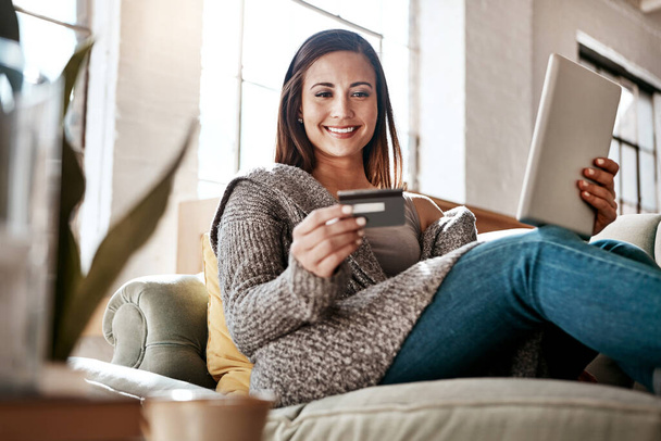 Online payment, digital tablet and credit card by woman on a sofa for online shopping in her home. Ecommerce, banking and girl with debit card for credit score, purchase or payment in living room. - Foto, imagen