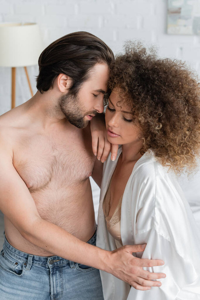 shirtless man seducing curly young girlfriend in white satin robe  - Φωτογραφία, εικόνα