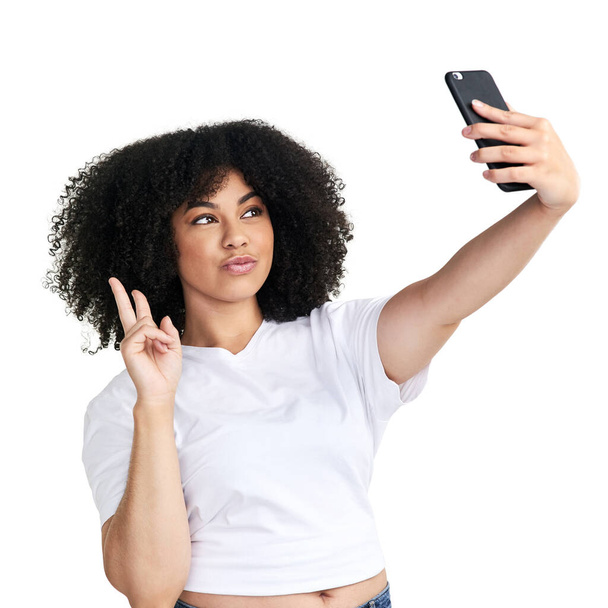 そんな風に冷静に。白い背景を背景に自撮りをするスマートフォンを使った魅力的な若い女性のスタジオショット - 写真・画像