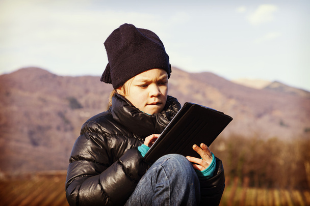Child looking her tablet, outdoors - Photo, image