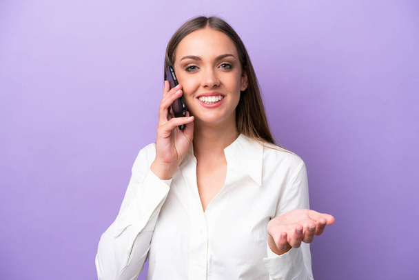 Young caucasian woman isolated on purple background keeping a conversation with the mobile phone with someone - Photo, image
