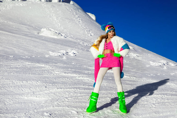 Beautiful sexy woman is wearing white fur, winter hat, scarf and winter boots. Attractive young girl in mountains. - Foto, Imagen