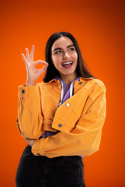 Позитивна молода жінка, показуючи ок жест ізольовано на помаранчевому
 - Фото, зображення