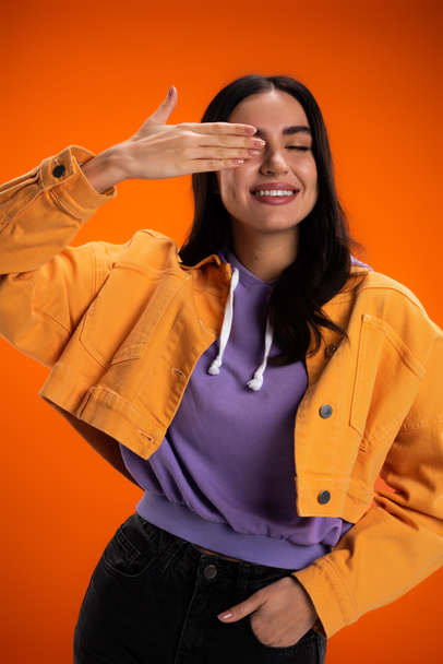 Positive woman in hoodie and jacket posing isolated on orange - Photo, Image